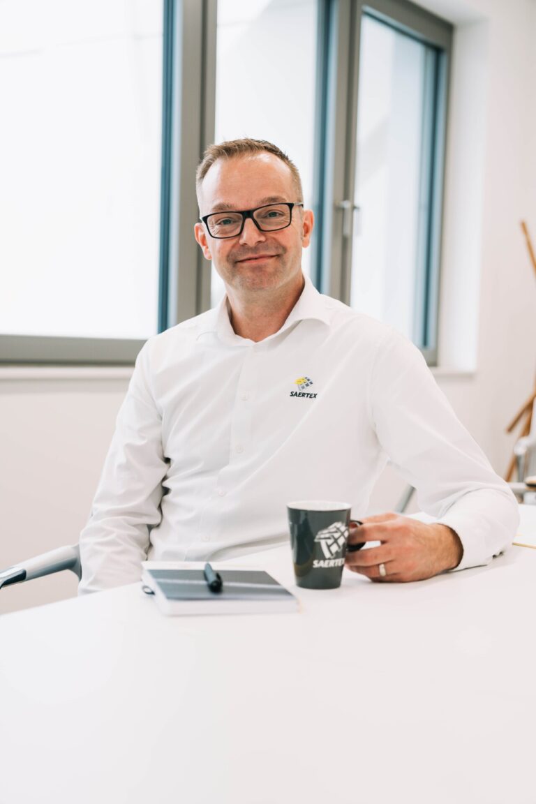 Mann mit Brille und weißem Hemd, der an einem Tisch sitzt